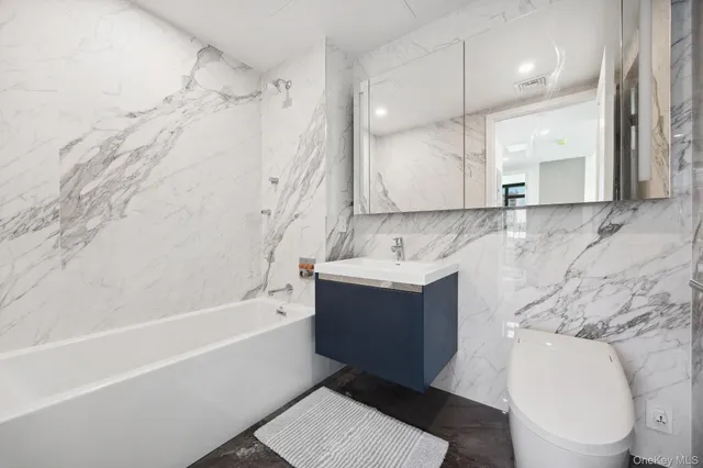 a bathroom with a bathtub shower sink vanity and toilet