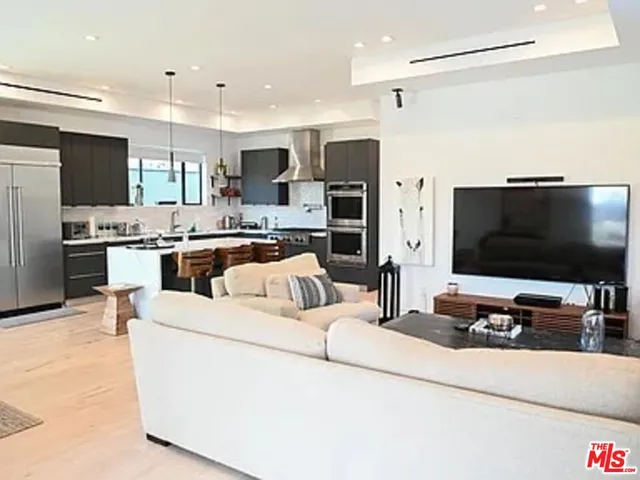 a living room with stainless steel appliances furniture and a flat screen tv