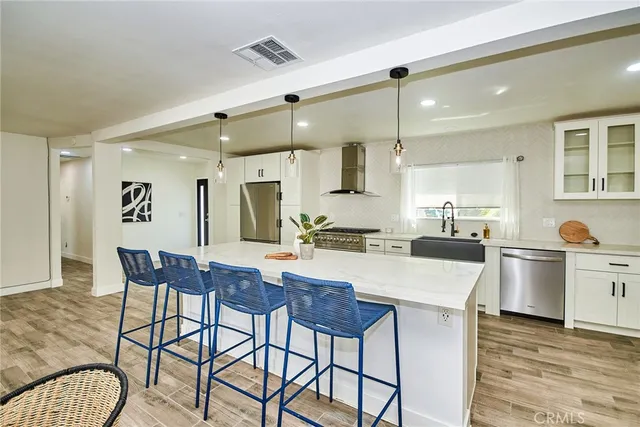 a kitchen with stainless steel appliances kitchen island granite countertop a dining table chairs and white cabinets