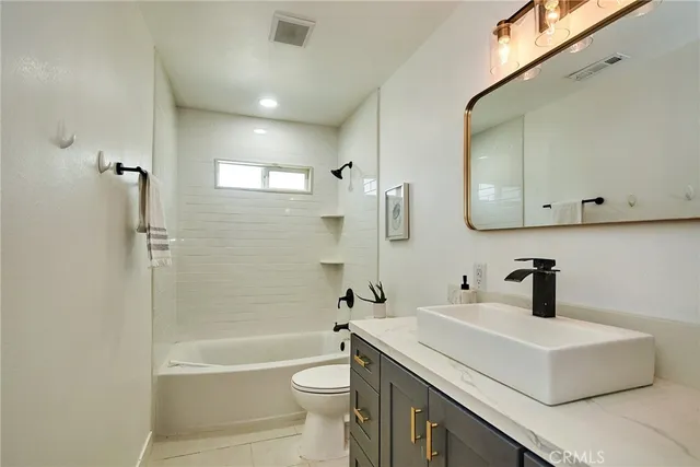 a bathroom with a sink a toilet a mirror a vanity and bathtub