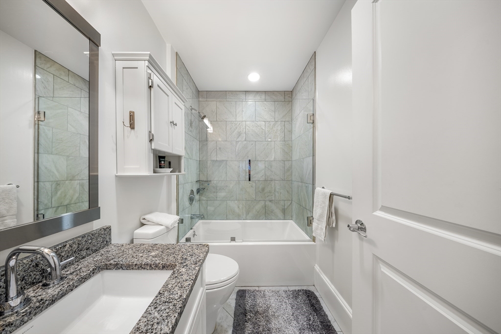 616 East 4th Street, Unit 301 Boston, MA 02127 - Photo 9 of 13 a bathroom with a granite countertop tub sink and mirror