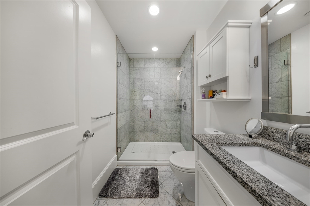 616 East 4th Street, Unit 301 Boston, MA 02127 - Photo 10 of 13 a bathroom with a granite countertop sink a toilet and shower