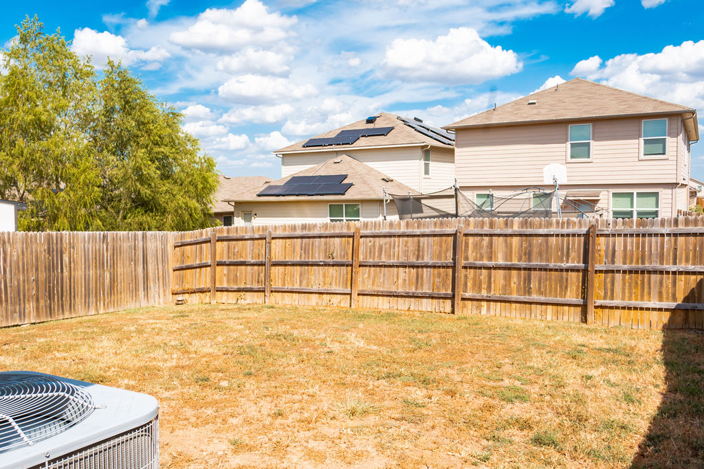 14915 Talus Road Manor, TX 78653 - Photo 17 of 20 A tall wooden privacy fence encloses the level lawn area under open skies.