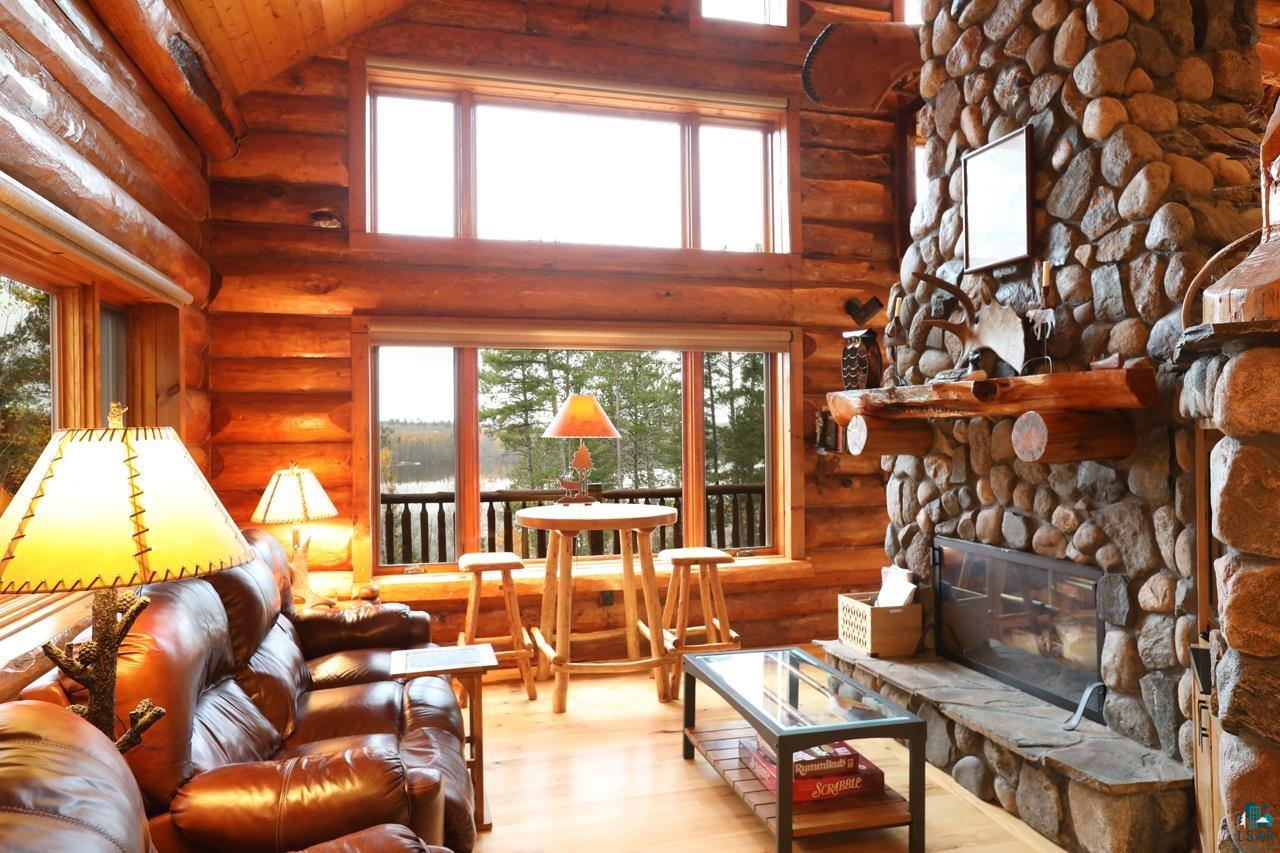 7236 Far North Road Orr, MN 55771 - Photo 5 of 42 Living area featuring log walls, wood finished floors, a stone fireplace, plenty of natural light, and high vaulted ceiling