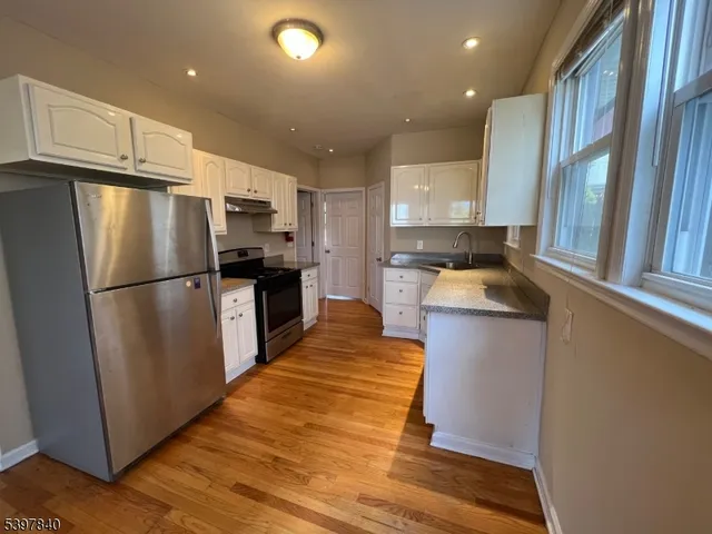 a kitchen with granite countertop a refrigerator a sink dishwasher a stove top oven a refrigerator and cabinets