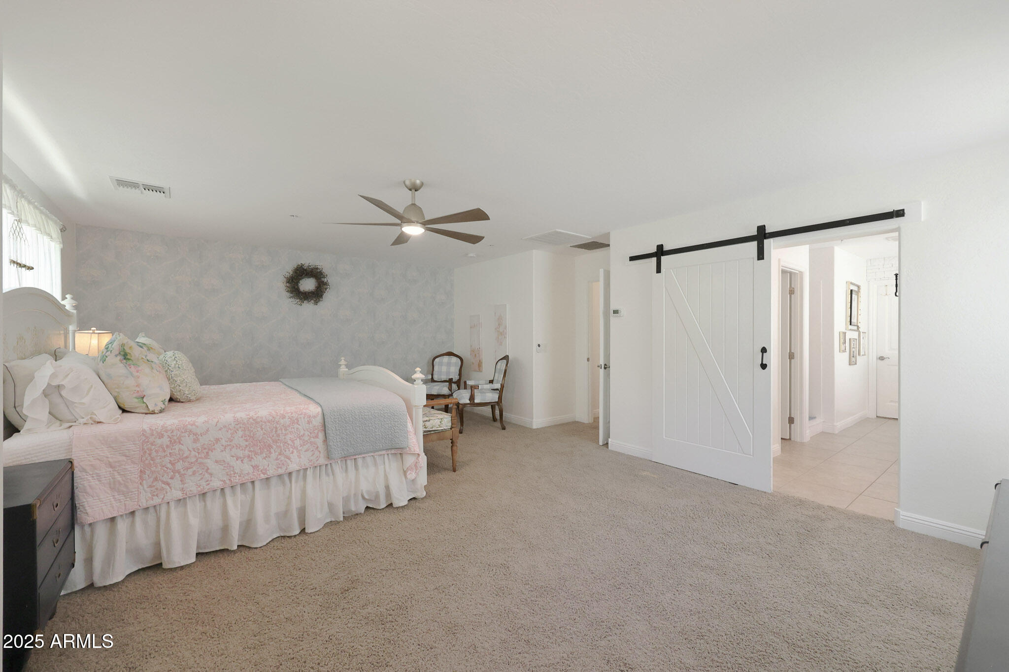 20563 West White Rock Road Buckeye, AZ 85396 - Photo 25 of 44 a spacious bedroom with two beds and a chandelier