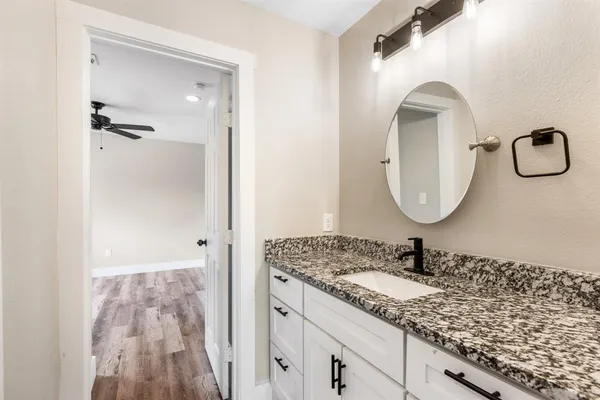 a bathroom with a granite countertop sink a mirror and shower