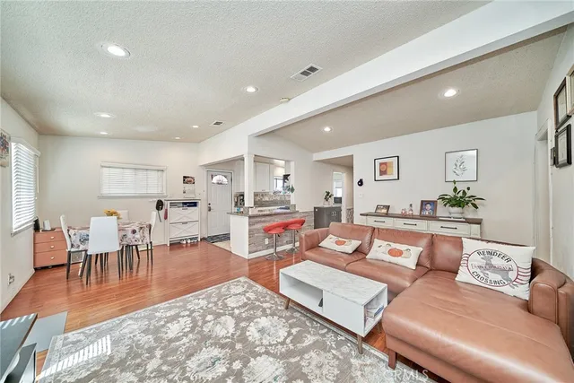 a living room with furniture a wooden floor and next to dining room