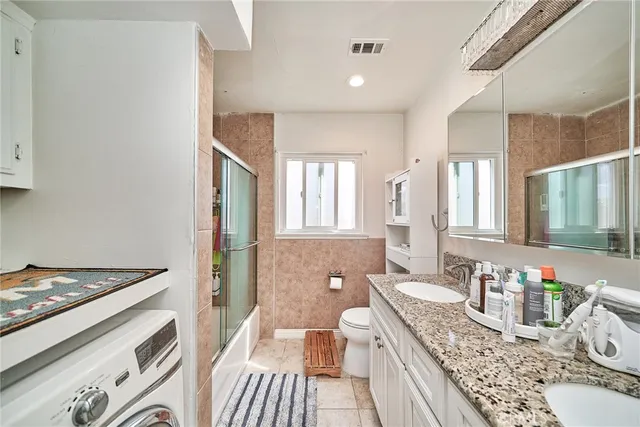 a spacious bathroom with a granite countertop double vanity sink a mirror and a shower