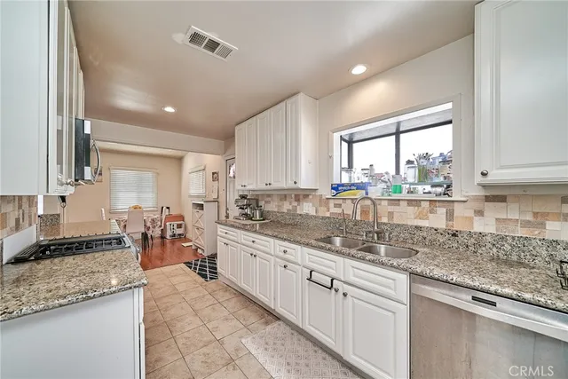 a kitchen with stainless steel appliances granite countertop a sink stove and cabinets