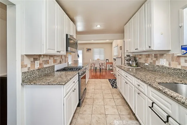a large kitchen with granite countertop a sink and cabinets