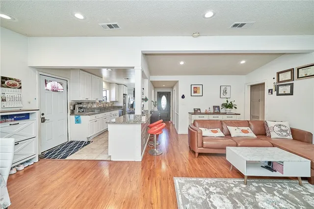 a living room with stainless steel appliances kitchen island granite countertop furniture and a wooden floor