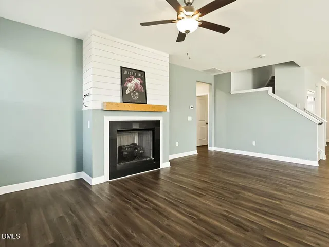a view of an empty room with wooden floor fireplace and a window