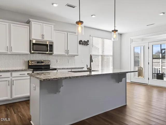 a kitchen with stainless steel appliances granite countertop a sink a stove and a refrigerator