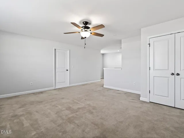 an empty room with windows and ceiling fan