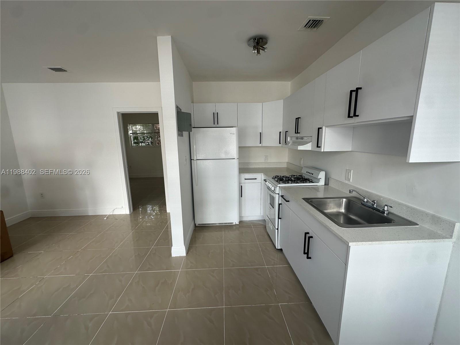 740 84th Street, Unit 3 Miami Beach, FL 33141 - Photo 4 of 12 a kitchen with a stove a refrigerator and a sink