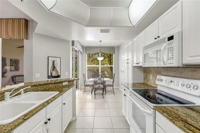 a kitchen with granite countertop a sink a counter top space appliances and cabinets
