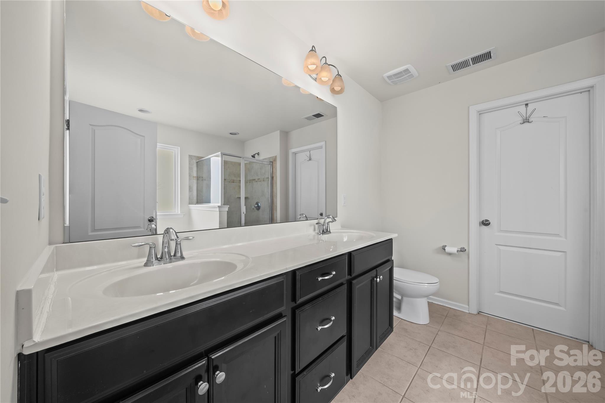 10666 Sapphire Trail Davidson, NC 28036 - Photo 21 of 34 a spacious bathroom with a double vanity sink a toilet and a mirror