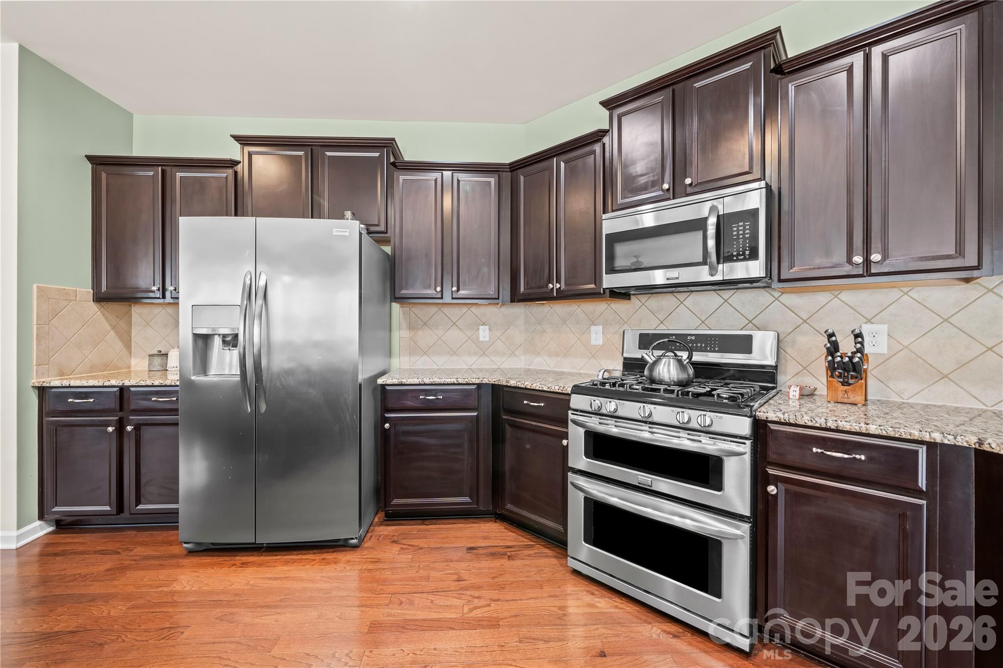 10666 Sapphire Trail Davidson, NC 28036 - Photo 8 of 34 a kitchen with granite countertop a refrigerator stove and microwave