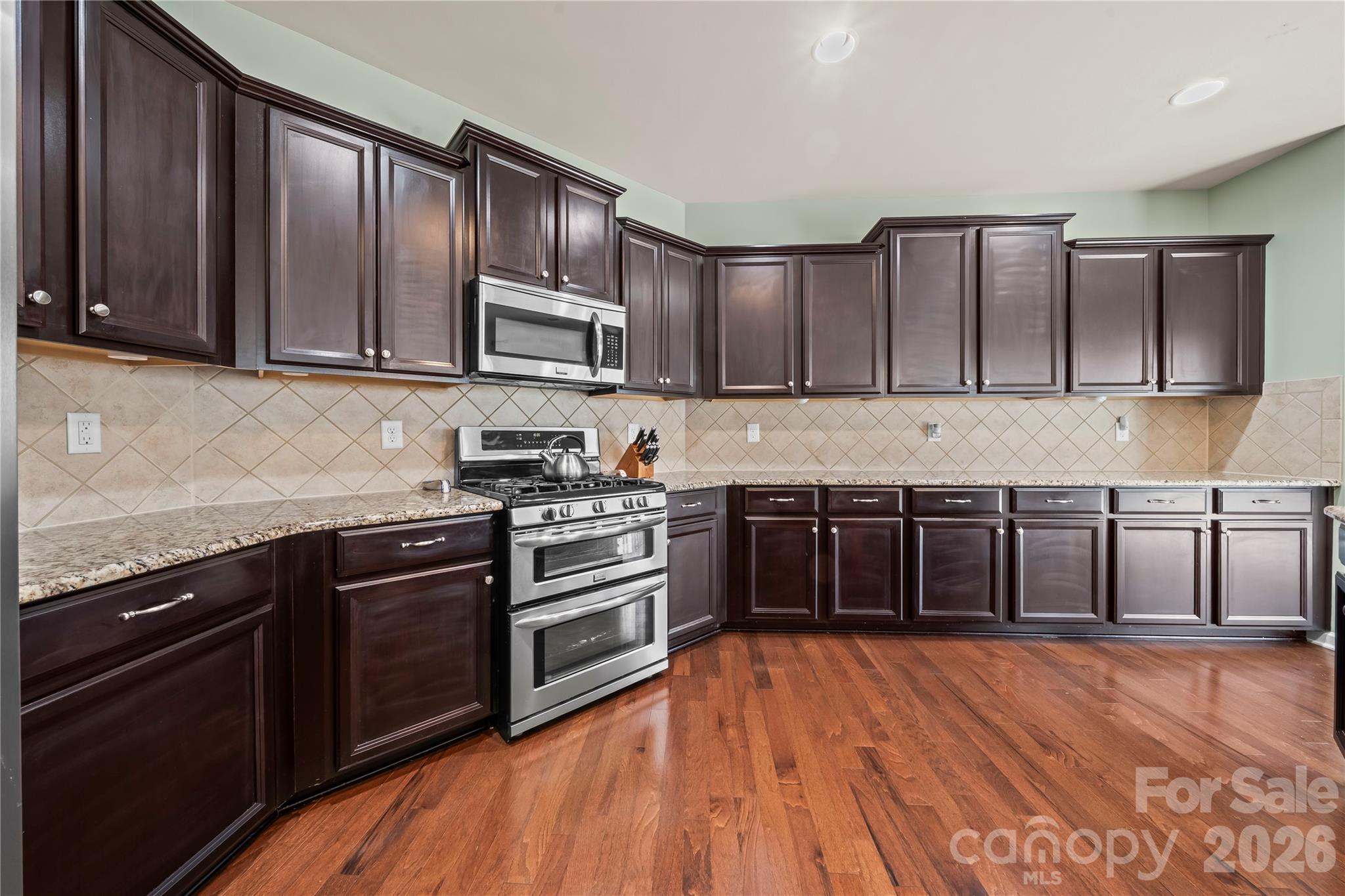 10666 Sapphire Trail Davidson, NC 28036 - Photo 9 of 34 a kitchen with stainless steel appliances granite countertop wooden cabinets a stove top oven a sink and dishwasher