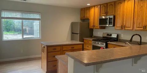 a kitchen with stainless steel appliances granite countertop a sink refrigerator stove and microwave