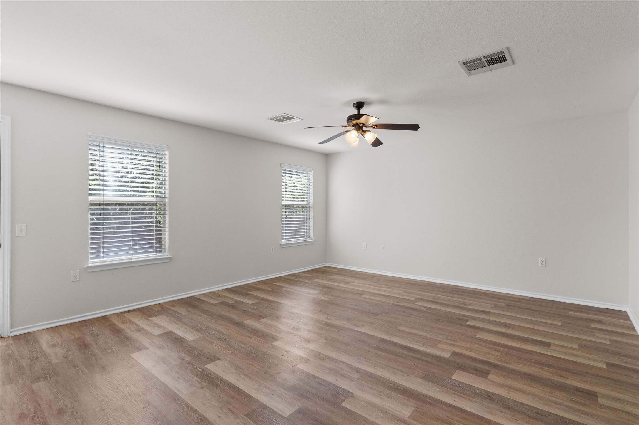 5825 Silver Screen Drive Austin, TX 78747 - Photo 7 of 40 Well-lit living area featuring rich hardwood flooring and practical window blinds.