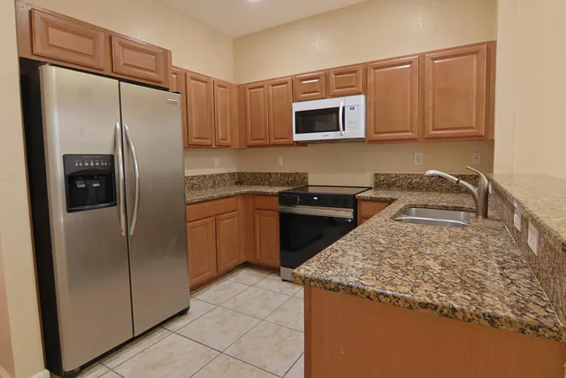 a kitchen with stainless steel appliances granite countertop a refrigerator a stove and a sink with wooden floor