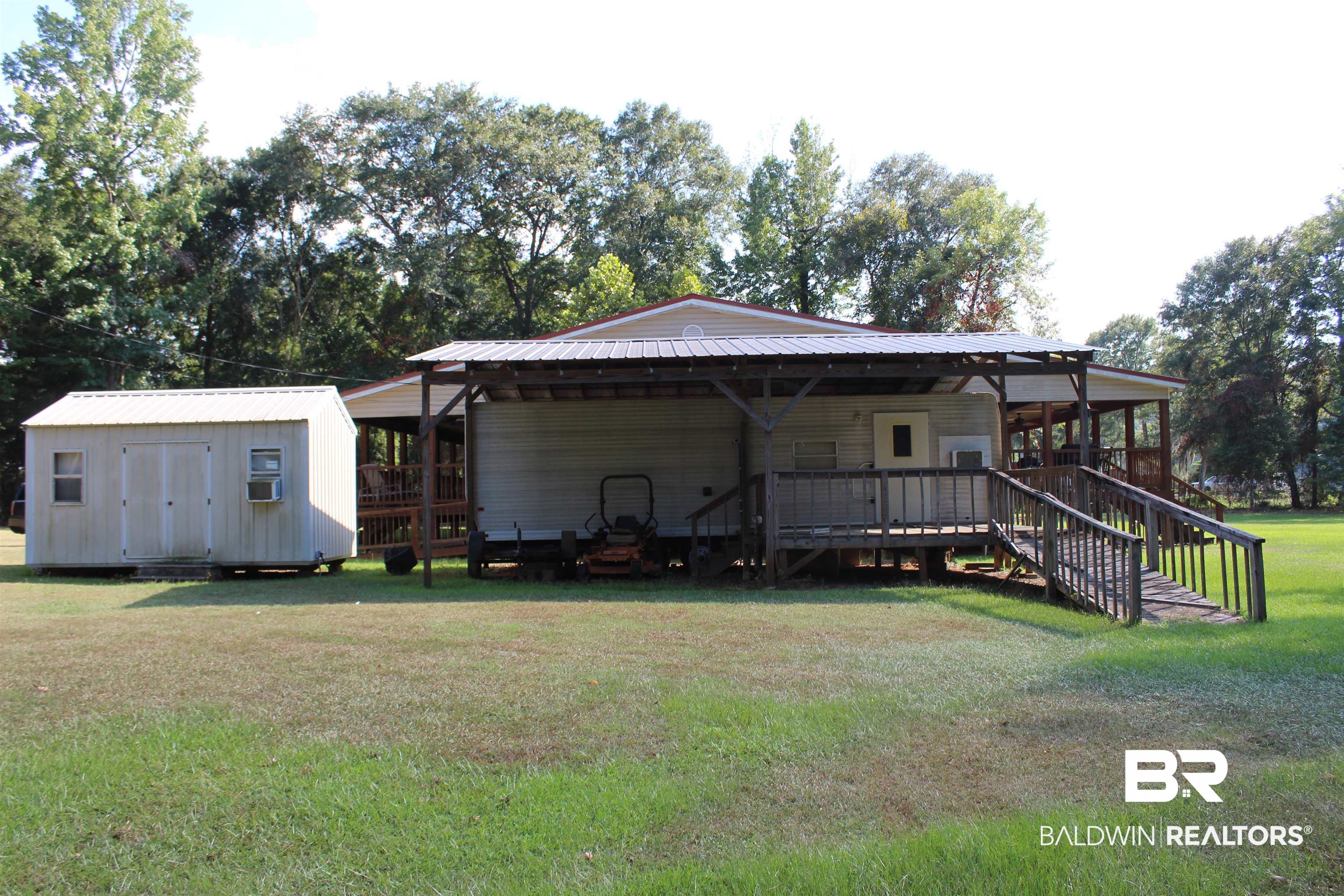 7258 Henderson Road Lowndesboro, AL 36752 - Photo 19 of 22 Back of property featuring a yard, a storage unit, a metal roof, a carport, and view of scattered trees