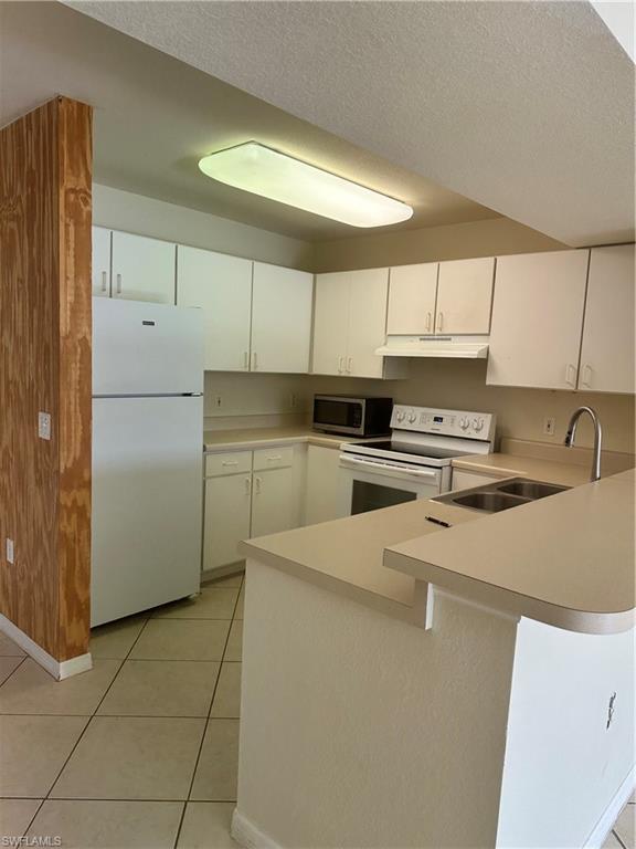 8234 Key Royal Circle, Unit 513 Naples, FL 34119 - Photo 3 of 5 a kitchen with stainless steel appliances a refrigerator sink and cabinets