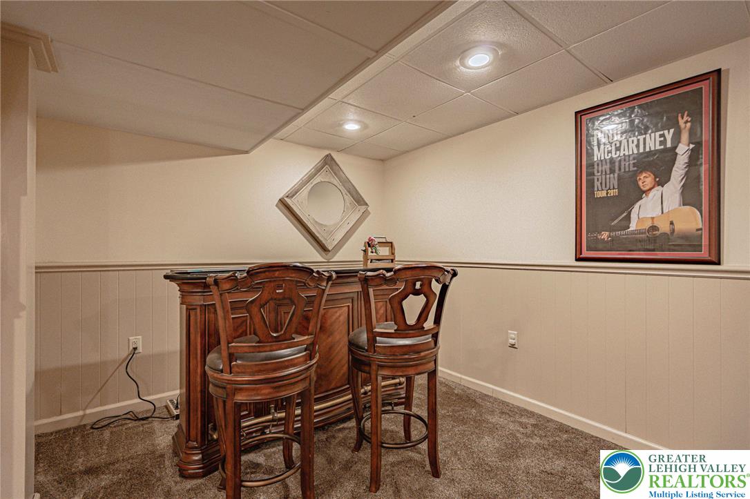 4542 Springfield Drive Coplay, PA 18037 - Photo 57 of 89 A well-lit recreational area features a classic bar setup with two elegant bar stools, perfect for entertaining.