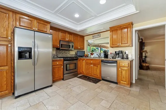 a kitchen with granite countertop a refrigerator a sink a stove top oven and cabinets