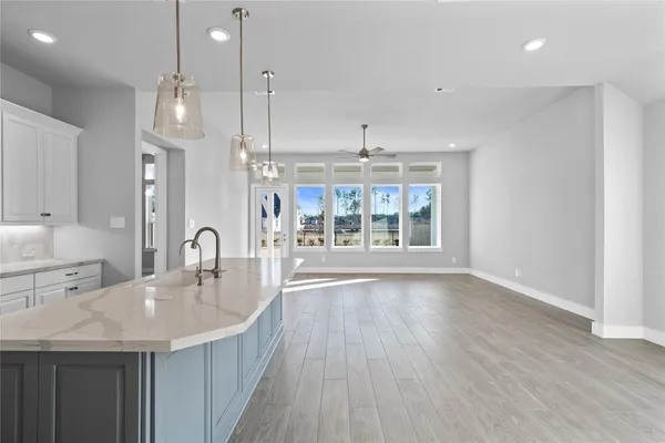 a kitchen with stainless steel appliances granite countertop a sink a oven a dining table and chairs with wooden floor