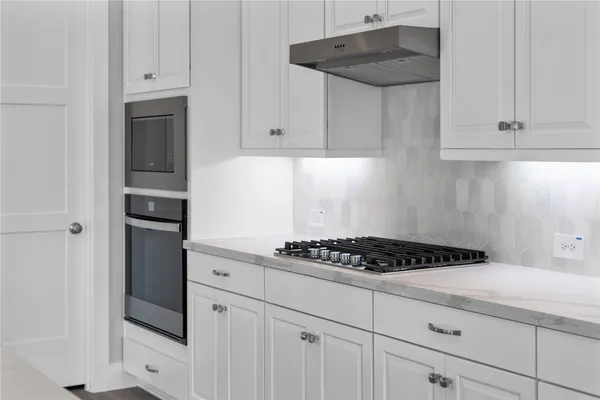 a kitchen with white cabinets and appliances