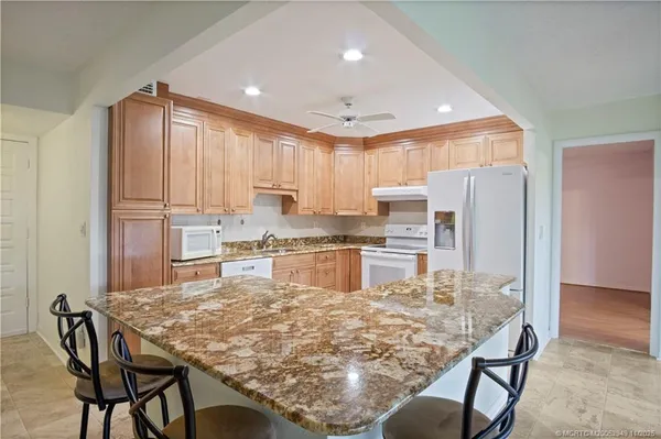 a kitchen with kitchen island granite countertop wooden cabinets a refrigerator and microwave