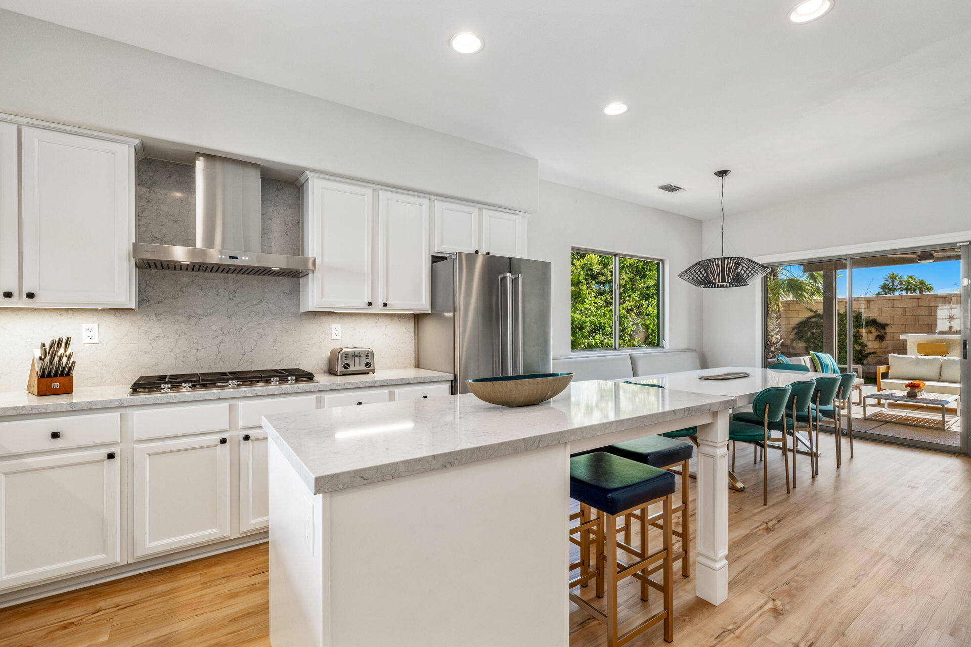 48674 Gibraltar Street Indio, CA 92201 - Photo 22 of 49 a kitchen with stainless steel appliances granite countertop a stove top oven a refrigerator a sink dishwasher a dining table and chairs with wooden floor