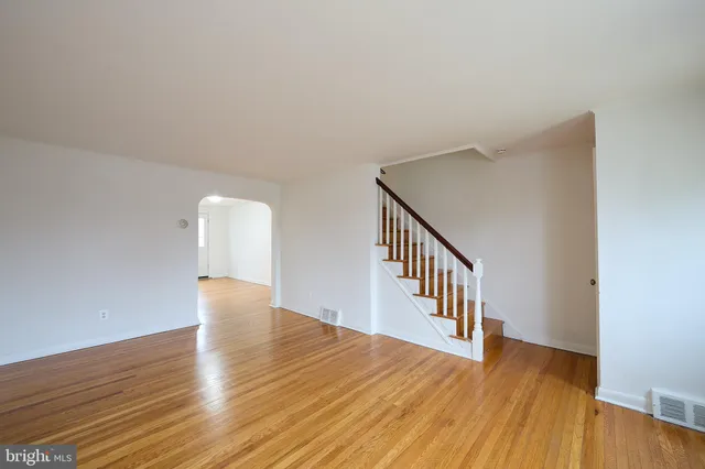a view of an empty room with wooden floor and stairs