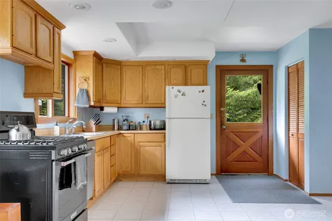 a kitchen with a refrigerator a stove top oven cabinetry and a window