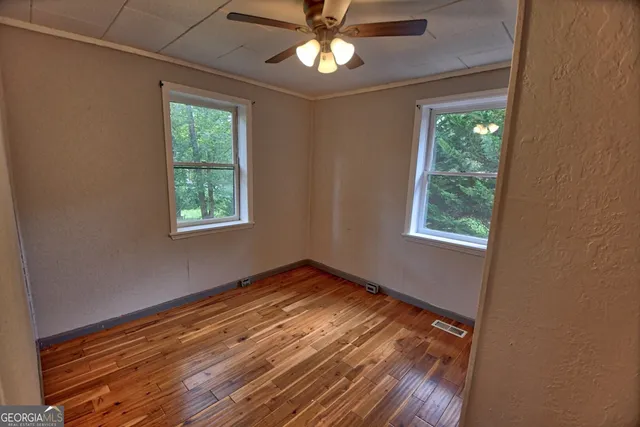 a view of empty room with wooden floor and fan