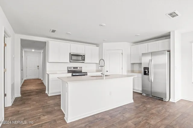 a kitchen with stainless steel appliances a refrigerator sink and white cabinets