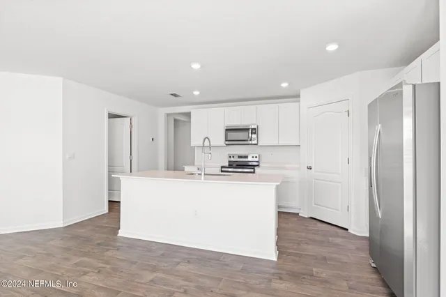 a view of kitchen with stainless steel appliances refrigerator stove microwave and cabinets