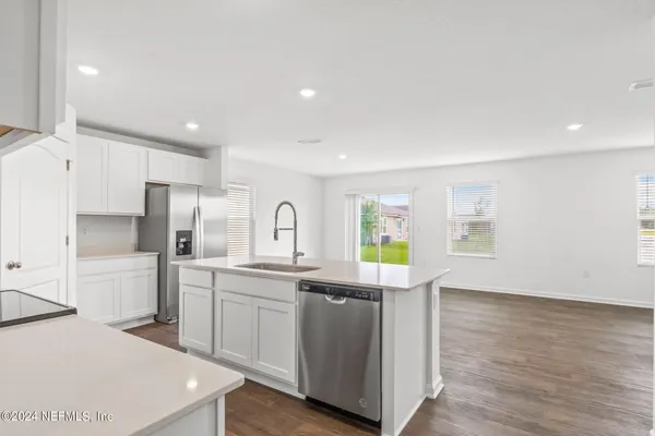 a kitchen with stainless steel appliances a sink a stove a refrigerator cabinets and a window