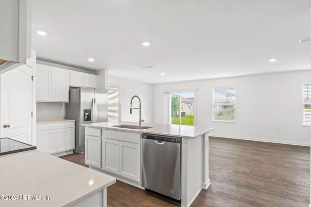 a kitchen with stainless steel appliances a sink a stove a refrigerator cabinets and a window