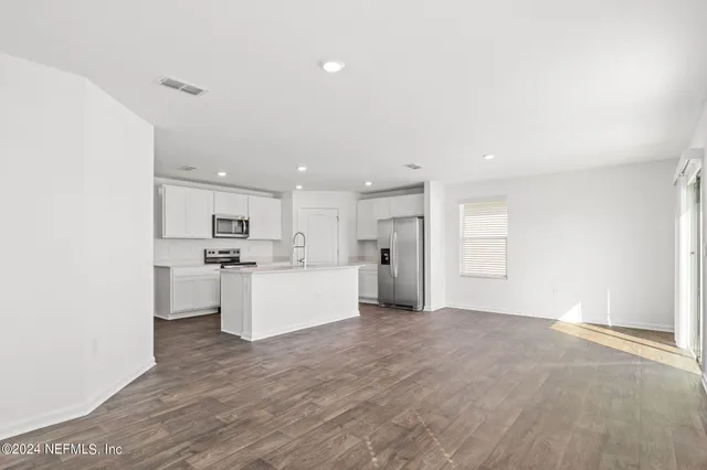 a view of kitchen with kitchen island a sink wooden floor and white appliances