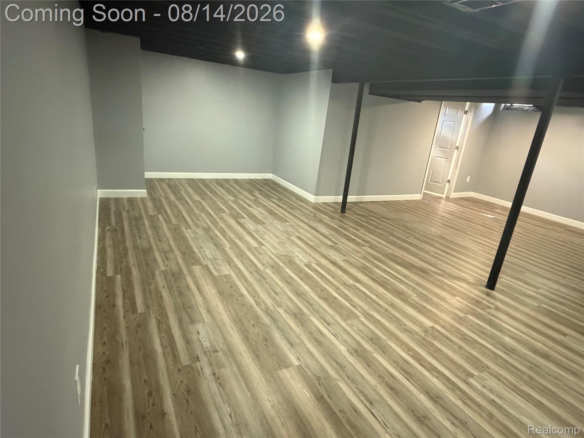 20698 Coachwood Road Riverview, MI 48193 - Photo 15 of 37 Spacious room featuring wood-finish flooring, light grey walls, white baseboards, and a black ceiling with recessed lighting