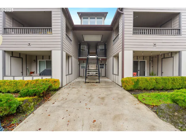 a view of a white house with a yard and potted plants