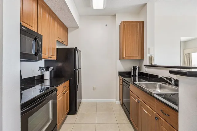 a kitchen with stainless steel appliances granite countertop a refrigerator a stove and a sink with wooden cabinets