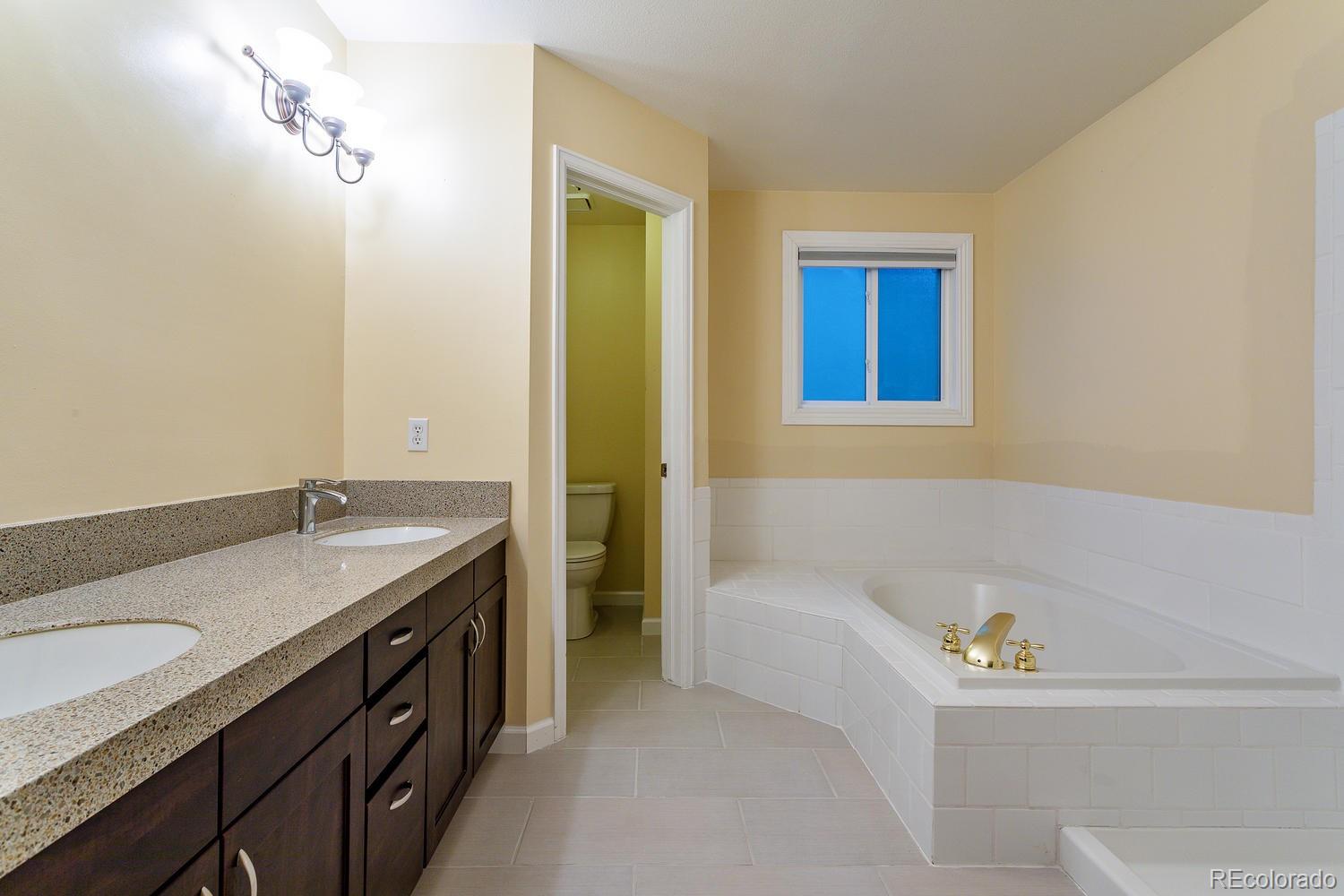9869 Spring Hill Drive Highlands Ranch, CO 80129 - Photo 19 of 37 a bathroom with a granite countertop sink and a bathtub