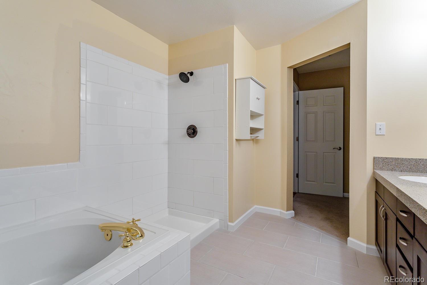 9869 Spring Hill Drive Highlands Ranch, CO 80129 - Photo 20 of 37 a bathroom with a bathtub and a shower