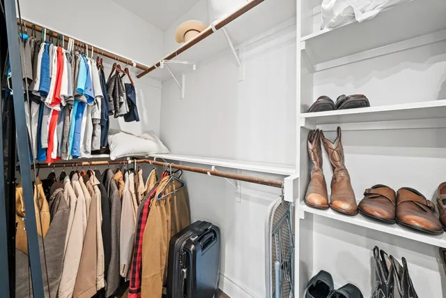 a view of walk in closet with clothes and shoes