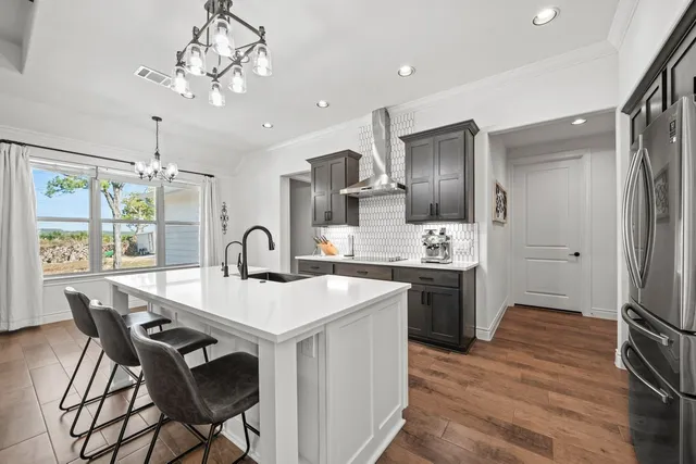 a kitchen with stainless steel appliances granite countertop a dining table chairs stove and refrigerator